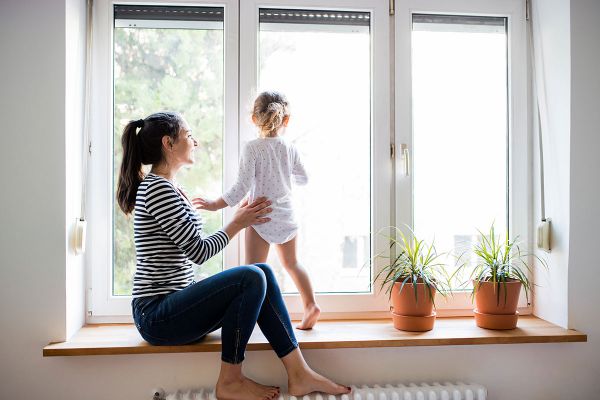 Mutter sitzt mit Kind auf der Fensterbank.