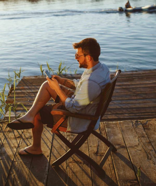 Mann entspannt sich im Urlaub - und steuert mit Smart-Home seine Rolläden und Lampen zu Hause