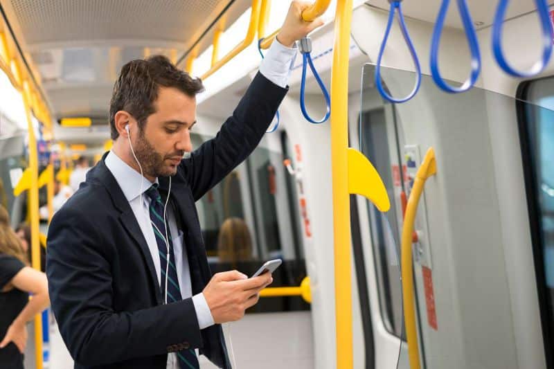 Mann steuert mit dem Smartphone seinen smarten Heizungsthermostat von der U-Bahn aus