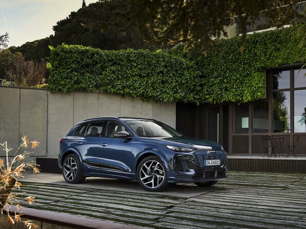 Audi Q6 e-tron in blau steht im Hof eines Hauses.