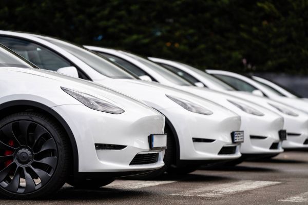 Fünf weiße Teslas. Diese stehen in einer Reihe nebeneinander.
