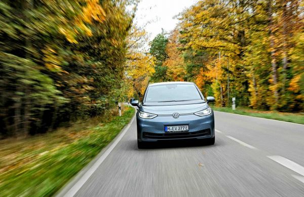 Ein blauer VW ID.3 fährt auf einer Straße durch eine Landschaft aus Bäumen.