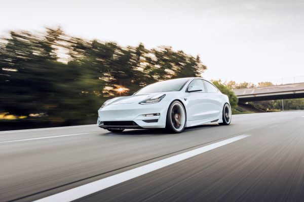 White Tesla driving along the road.