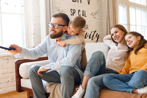 Familie schaut auf dem Sofa Fernsehen.