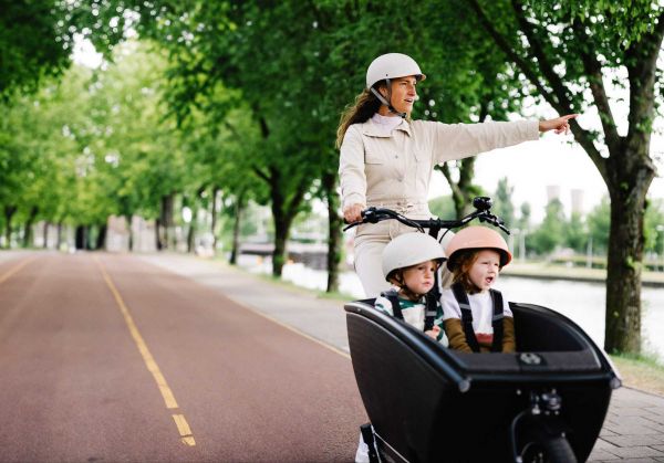 Frau fährt mit ihren Kindern ein Lastenfahrrad Urban Arrow Family