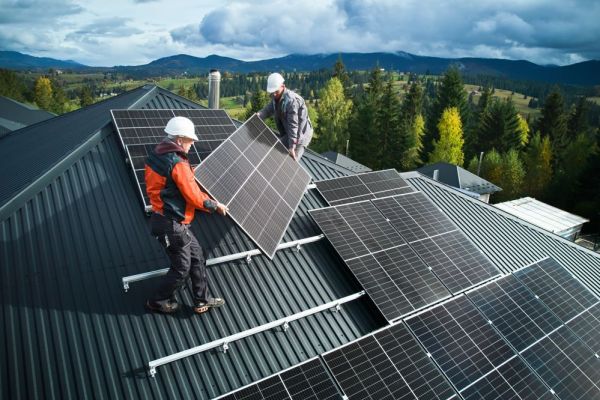 Monteure montieren eine PV-Anlage auf einem Hausdacht