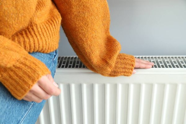 Person sitzt auf Plattenheizkörper